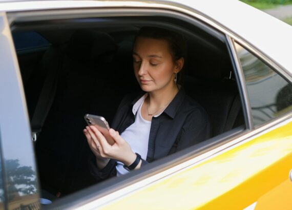 Kvinna i bilhytt tittar på telefon, kan användas för att hitta hundbilar.